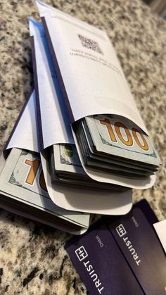 several stacks of money sitting on top of each other next to a passport and credit card