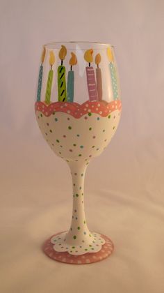 a wine glass with candles on it sitting in front of a white background and pink polka dot tablecloth