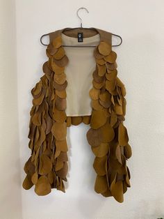 a brown jacket hanging on a wall next to a plant