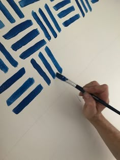 a man is painting on the wall with blue paint