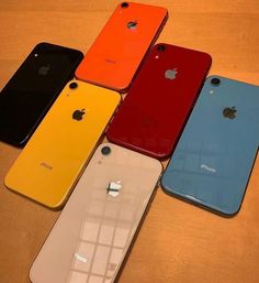 six different colored iphones sitting next to each other on a wooden table in front of an apple logo