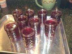 there are many glasses on the tray with jams in them and one is empty