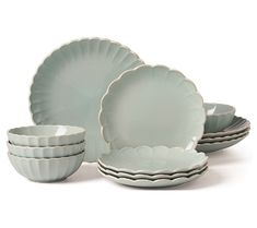 a set of dishes with scalloped rims and saucers in pale blue