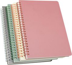 three spiral bound notebooks stacked on top of each other, one pink and the other green