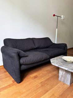 a black couch sitting on top of a hard wood floor next to a white table