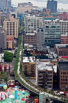 an aerial view of a city with lots of tall buildings and colorful umbrellas in the foreground