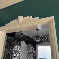 an ornate mirror frame in front of a green wall with black and white damask