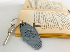 an open book with a keychain on it sitting next to a pair of keys