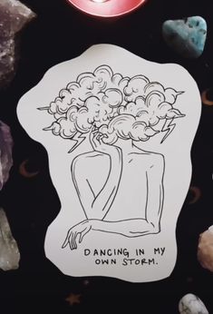 a sticker that says dancing in my own storm next to some rocks and candles