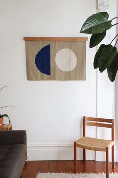 a living room with a couch, chair and artwork on the wall