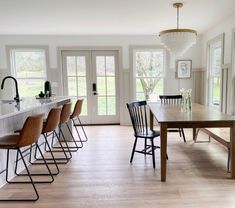 a dining room table and chairs in front of an open kitchen area with french doors