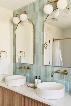 a bathroom with two sinks, mirrors and lights on the wall in front of it