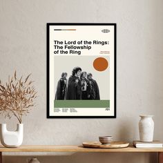 the lord of the rings poster hangs above a table with vases and potted plant