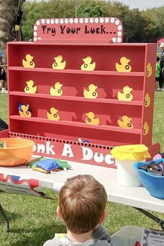 a little boy sitting in front of a red toy ducky game on a table