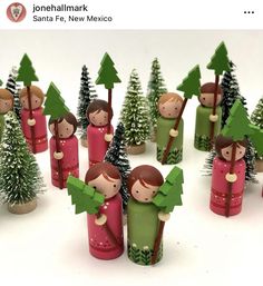 some little figurines are standing next to each other in front of christmas trees