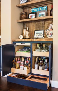 an open cabinet in the corner of a room with bottles on it and pictures above