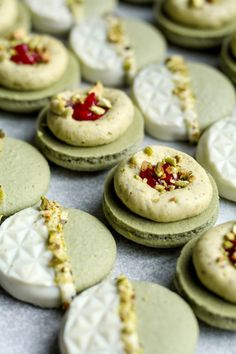 several cookies with white frosting and red toppings are arranged on a table top