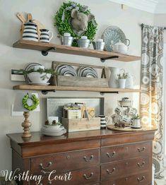 a wooden dresser topped with lots of dishes next to a shelf filled with cups and saucers