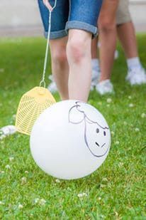 a white ball with a face drawn on it is being held by two people in the grass