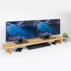 two computer monitors sitting on top of a wooden desk