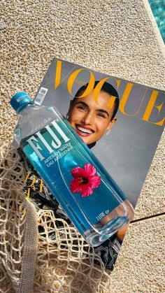 the magazine is laying on the ground next to a bottle of water and a flower