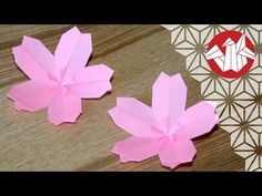 two pink paper flowers sitting on top of a wooden table