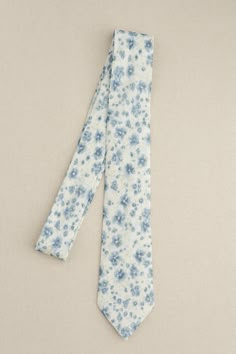 a tie with blue flowers on it is laying on the ground next to a wall