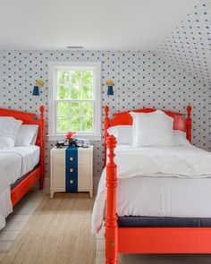 two beds in a room with blue and white wallpaper on the walls next to each other