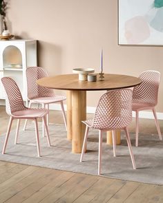 a dining room table with pink chairs and a white rug on the floor next to it