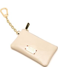 a white purse with a gold key chain hanging from it's front pocket, on a white background