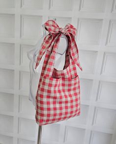 a red and white checkered bag with a bow on the front hanging from a metal stand