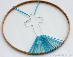 the cross is made out of blue thread and sits on top of a wooden hoop