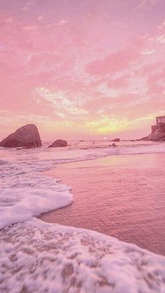 an ocean beach with waves coming in to shore and a pink sky above the water