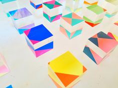 many different colored paper squares are arranged on the floor with one another in front of them