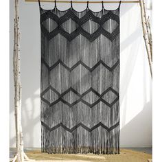 a black and white wall hanging next to some birch tree branches in front of a white wall