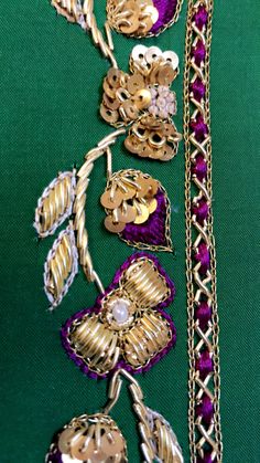 several pieces of jewelry are laying on a green tablecloth with gold chains and purple beads