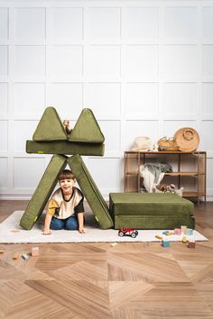 a young boy sitting on the floor in front of a green chair