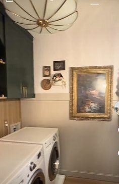 a washer and dryer in a room with pictures on the wall above it