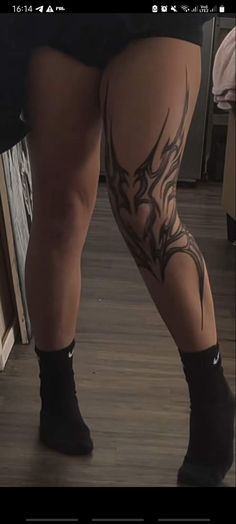 a woman's legs with tattoos on them and her leg in the middle of the floor