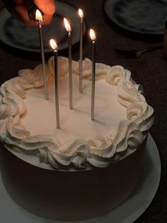 a person lighting candles on top of a cake