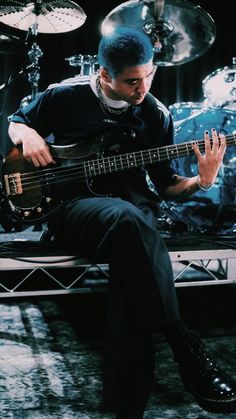 a man sitting on top of a bench playing a bass guitar