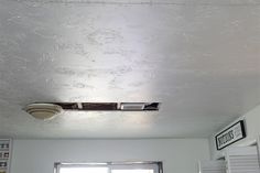 a ceiling fan is mounted on the wall above a window in a room with white walls