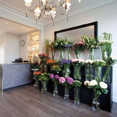 a bunch of vases filled with flowers sitting on top of a hard wood floor