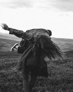 a person jumping up in the air to catch a frisbee on top of a hill