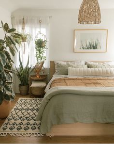 a bedroom with a bed, rug and plants in it