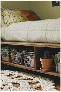 a bed that has some baskets under it on the floor next to a rug and pillow