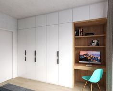 a room with white cupboards and a blue chair in front of a tv on the wall