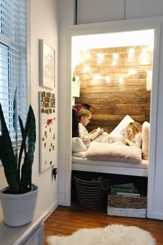 two children are sitting on a bed in their room with lights strung above the headboard