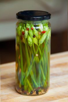 a jar filled with green flowers sitting on top of a wooden table