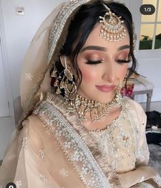 a woman wearing a bridal outfit with jewelry on her head and veil over her face